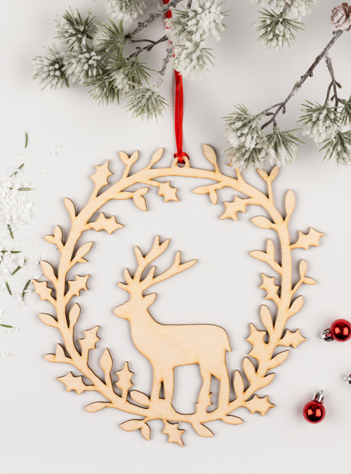 Photograph of a wooden deer wreath. handmade wooden silhoette of a deer surrounded by a festive wreath.
