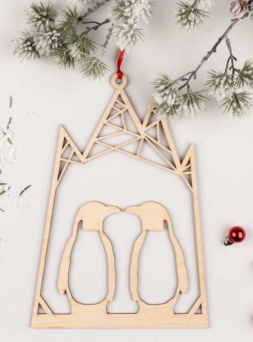 wooden penguin decoration featuring 2 penguins facing each other within an icey looking mountain. made from birch ply
