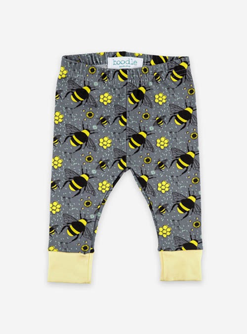 Grey organic baby leggings with a repeat pattern of bees, honeycomb anf flowers with yellow cuffs.