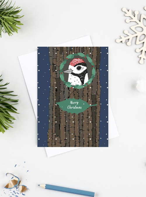 Woodpecker Christmas card featuring a wood pecker in his home (a tree) with a sign on holly beneath saying 'Merry Christmas'